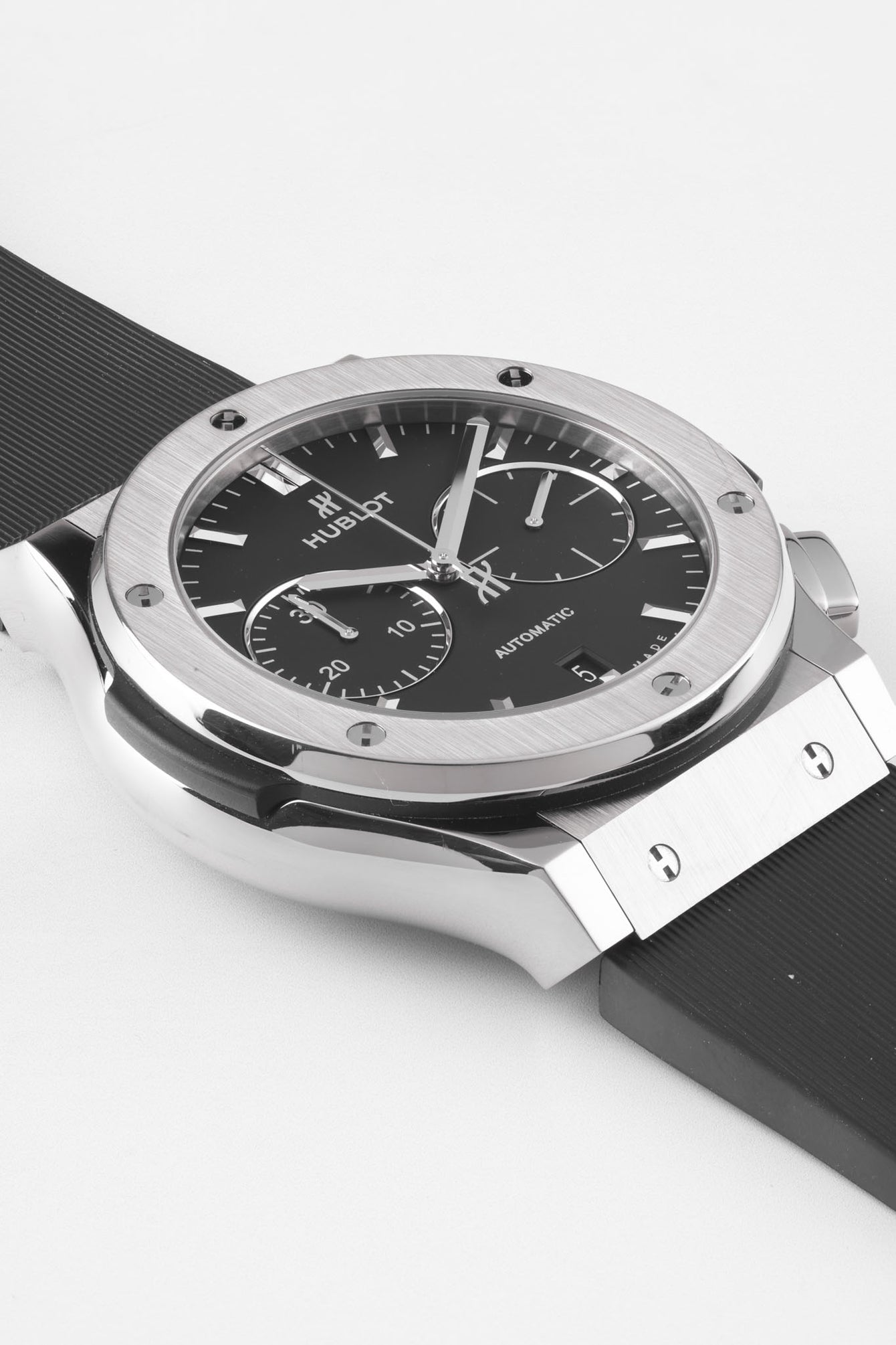Close-up of a Hublot Classic Fusion chronograph with a black dial and rubber strap, highlighting the brushed bezel, subdials, and polished case details against a clean white background.