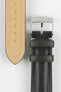 Close-up of two black leather watch strap sections on a light grey background. One section features a polished silver tang buckle with an engraved logo and two leather keepers, while the other shows the underside of the strap in tan suede with a row of evenly spaced adjustment holes. The leather has a smooth, slightly pebbled texture with light contrast stitching near the buckle.