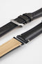 Angled close-up of a black leather watch strap on a light grey background, showing multiple strap sections separated and laid side by side. One section features a polished silver tang buckle with an engraved logo and two leather keepers, while the others display the smooth, slightly pebbled black leather exterior and the tan suede underside near the lugs. The strap includes evenly spaced adjustment holes and visible stitching, highlighting its construction and premium finish.