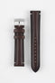 Two burgundy leather watch strap pieces displayed vertically on a light grey background. One strap section features a polished silver tang buckle with an engraved logo and two leather keepers, while the other shows a tapered end with a row of evenly spaced adjustment holes. The leather has a smooth, slightly pebbled texture with subtle light stitching near the lugs, highlighting its refined finish.