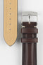 Close-up of a burgundy leather watch strap on a light grey background, showing one section with a polished silver tang buckle featuring an engraved logo and two leather keepers. Beside it, the opposite strap section displays the tan suede underside with a row of evenly spaced adjustment holes. The leather has a smooth, slightly pebbled texture with light contrast stitching near the buckle, highlighting the strap’s construction and finish.