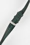 Angled close-up of a dark green leather watch strap set against a light grey background, featuring a polished silver tang buckle with an engraved logo and two matching leather keepers. The strap shows a smooth, slightly pebbled texture with a row of adjustment holes along its length, and subtle contrast stitching near the lugs, highlighting its refined construction and finish.