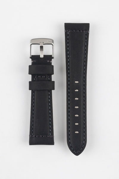 Two black leather watch strap pieces displayed vertically on a light grey background, featuring a matte, slightly textured finish with dark grey stitching. One strap section includes a brushed silver tang buckle with an engraved logo and two leather keepers, while the other shows a tapered end with a row of evenly spaced oval adjustment holes. The clean lines and stitched edges highlight the strap’s durable, contemporary design.