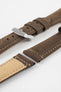 Brown leather watch strap with light stitching, shown in angled close-up with a silver buckle, adjustment holes, and tan suede underside.