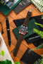 Flat-lay of a Tudor GMT watch with a black dial and red-and-blue bezel on a brown leather strap, arranged with a pen, wallet, greenery, and accessories on a wooden surface.