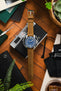 Flat-lay of a Unimatic dive watch with a blue dial on a tan leather strap, placed over a vintage camera and surrounded by tools, greenery, and accessories on a wooden surface.