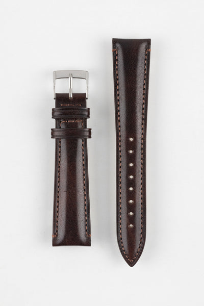 Brown leather watch strap with contrast stitching, shown vertically with a silver buckle and adjustment holes on a light grey background.
