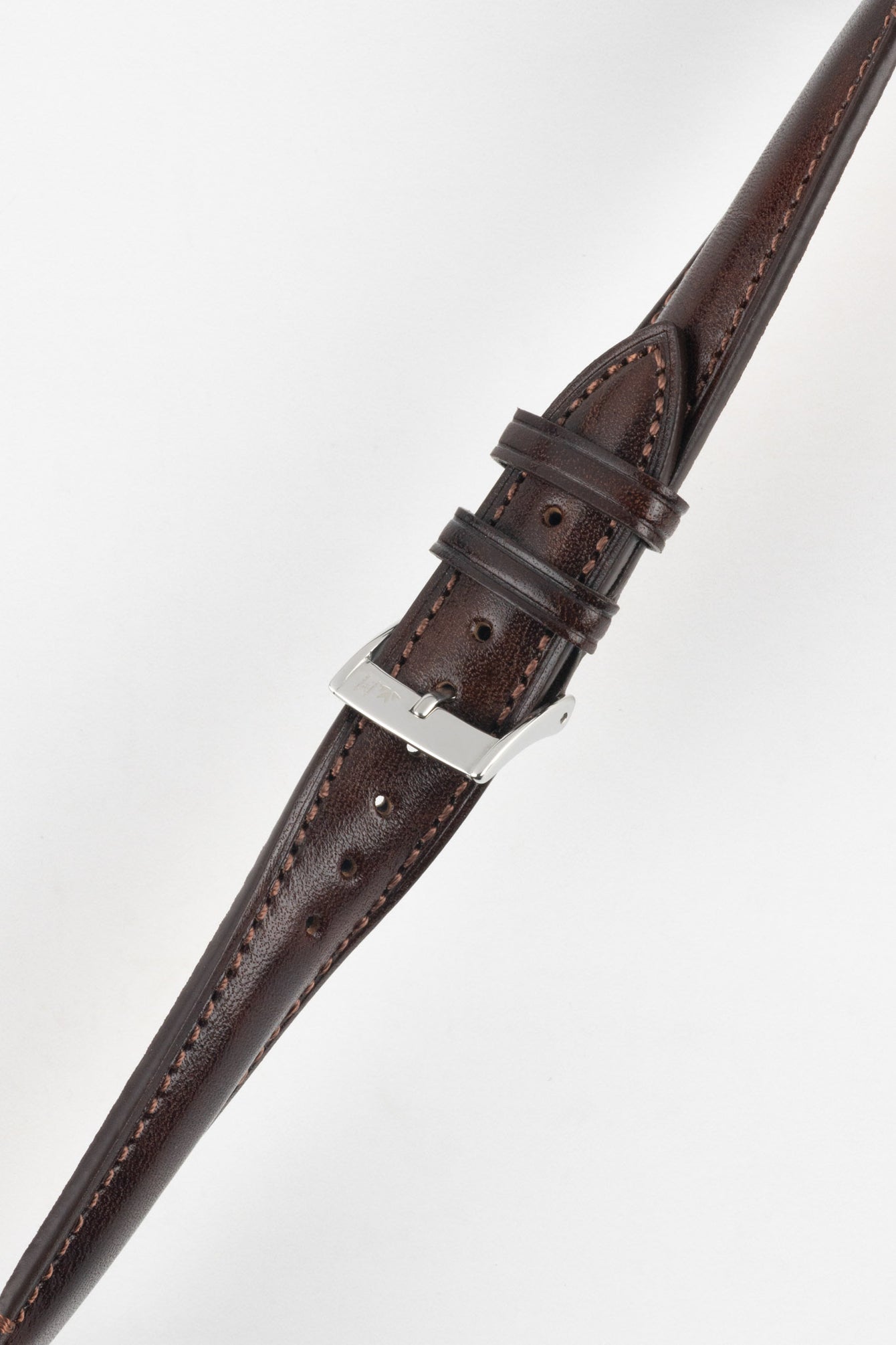 Brown leather watch strap with contrast stitching, shown in angled close-up with a silver buckle and adjustment holes.