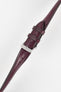 Burgundy leather watch strap with matching stitching, shown in angled close-up with a silver buckle and adjustment holes.