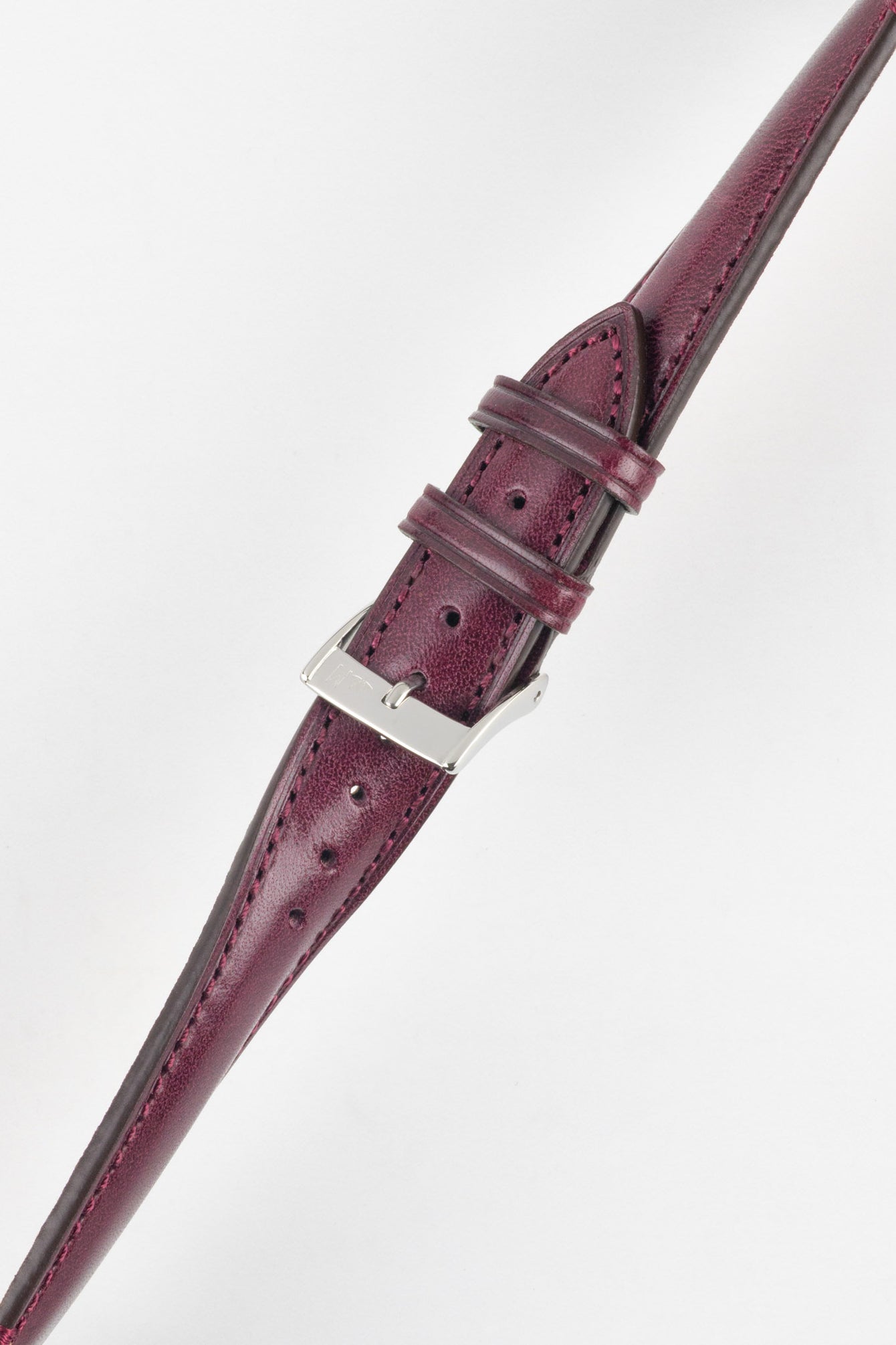 Close-up product shot of a burgundy leather watch strap with a smooth, slightly textured finish and matching burgundy stitching, fitted with a polished silver pin buckle. The strap is shown at an angle on a plain light background, highlighting the rich colour, stitching detail, adjustment holes, and buckle hardware.
