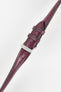 Close-up product shot of a burgundy leather watch strap with a smooth, slightly textured finish and matching burgundy stitching, fitted with a polished silver pin buckle. The strap is shown at an angle on a plain light background, highlighting the rich colour, stitching detail, adjustment holes, and buckle hardware.