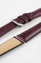 Burgundy leather watch strap with matching stitching, shown in angled close-up with a silver buckle, adjustment holes, and beige suede underside.