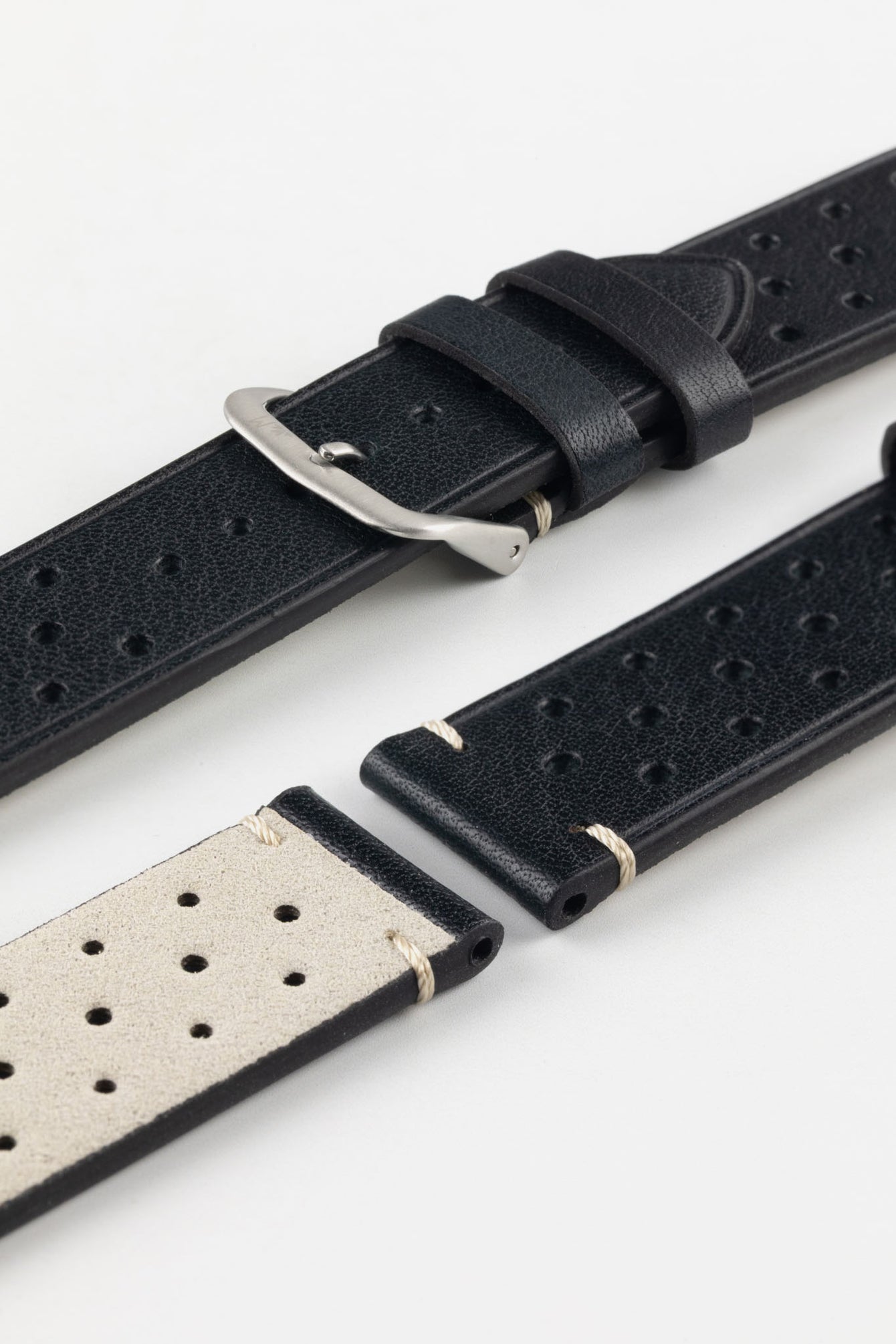 
A detailed, high-angle shot of a black Morellato Brahms watch strap, unbuckled and laid flat against a white background. The image highlights the perforated design and the white stitching at the short end, showing the light-coloured lining of the strap.