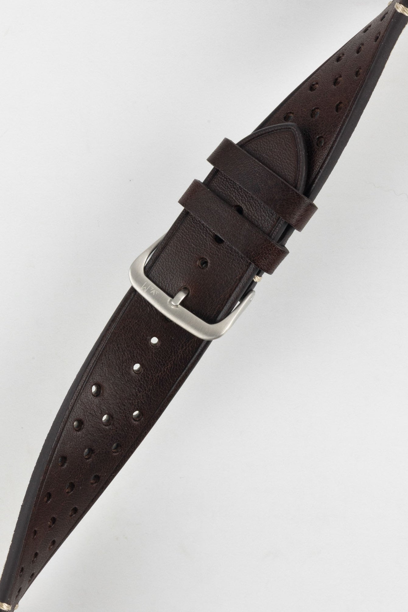A close-up, high-angle shot of a dark brown Morellato Brahms watch strap, buckled and resting diagonally against a white background. The image focuses on the rally-style perforations and the satin-finished steel buckle.