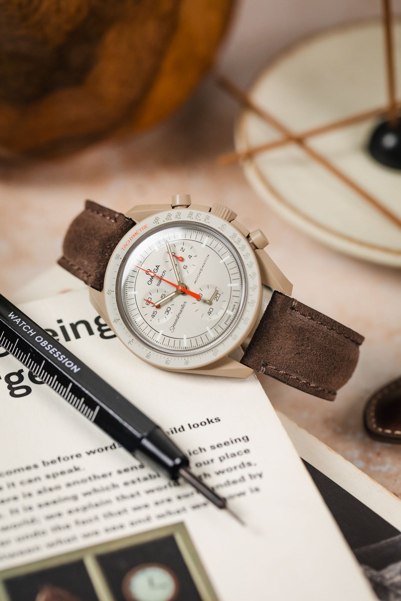 Morellato SCHUMANN brown suede watch strap with Omega MoonSwatch on a table. Classic watch strap options for your collection.