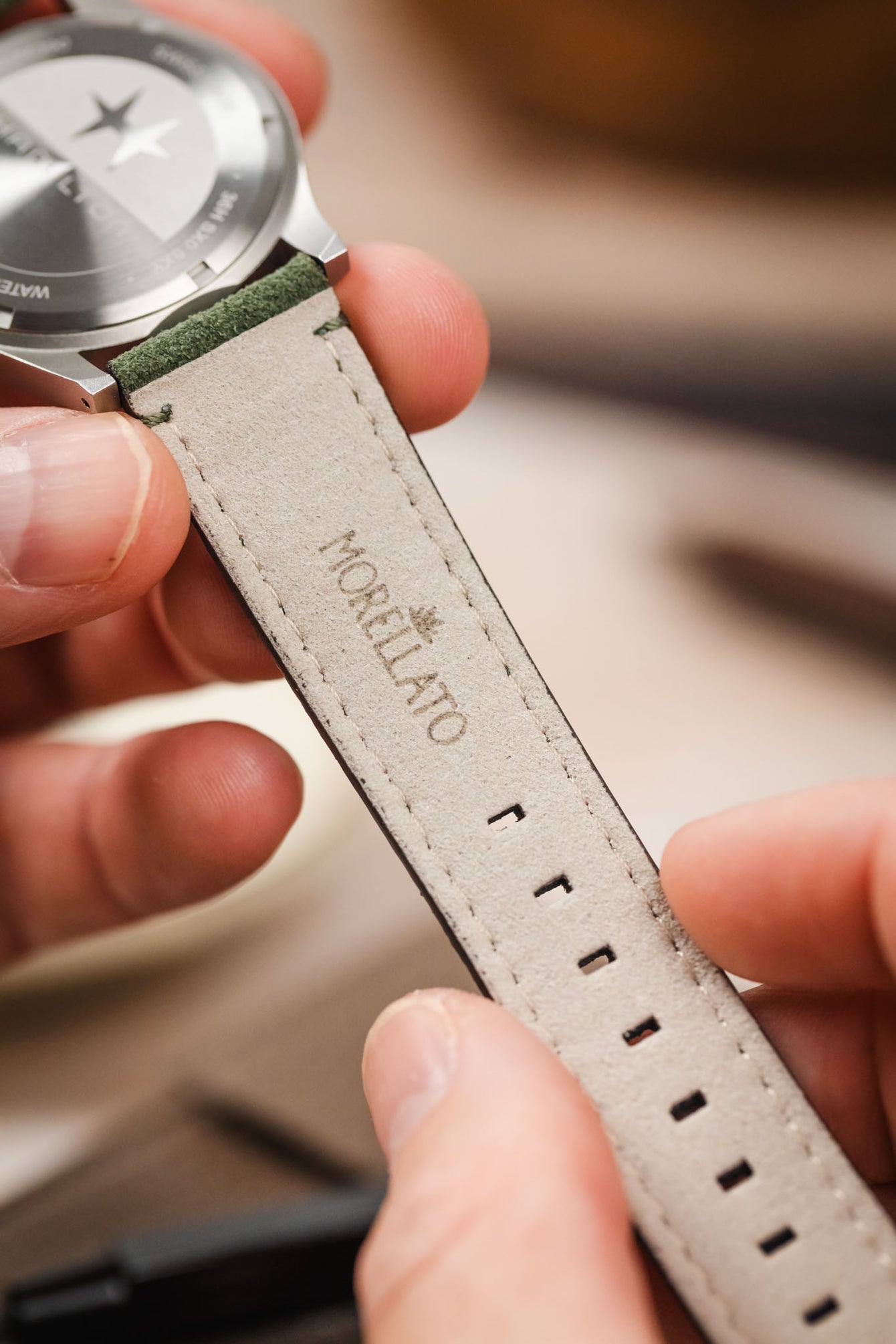 Hands holding Hamilton Khaki Field watch, showcasing the Morellato SCHUMANN green suede strap's interior. Easy-to-install watch straps.