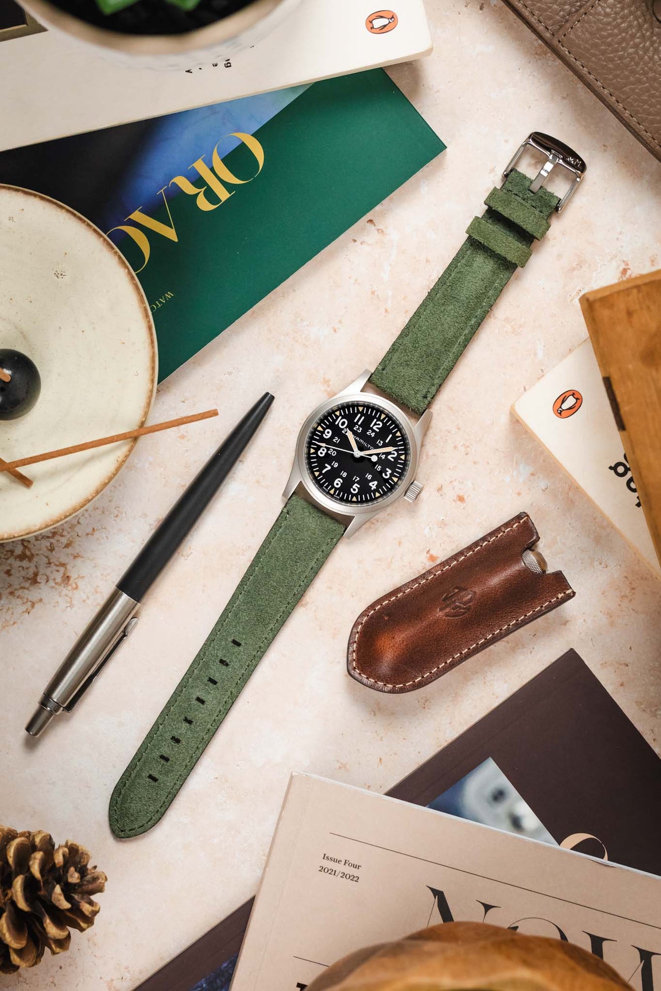 Overhead shot of Morellato SCHUMANN green suede watch strap with Hamilton Khaki Field watch and desk accessories. Shop stylish watch straps.