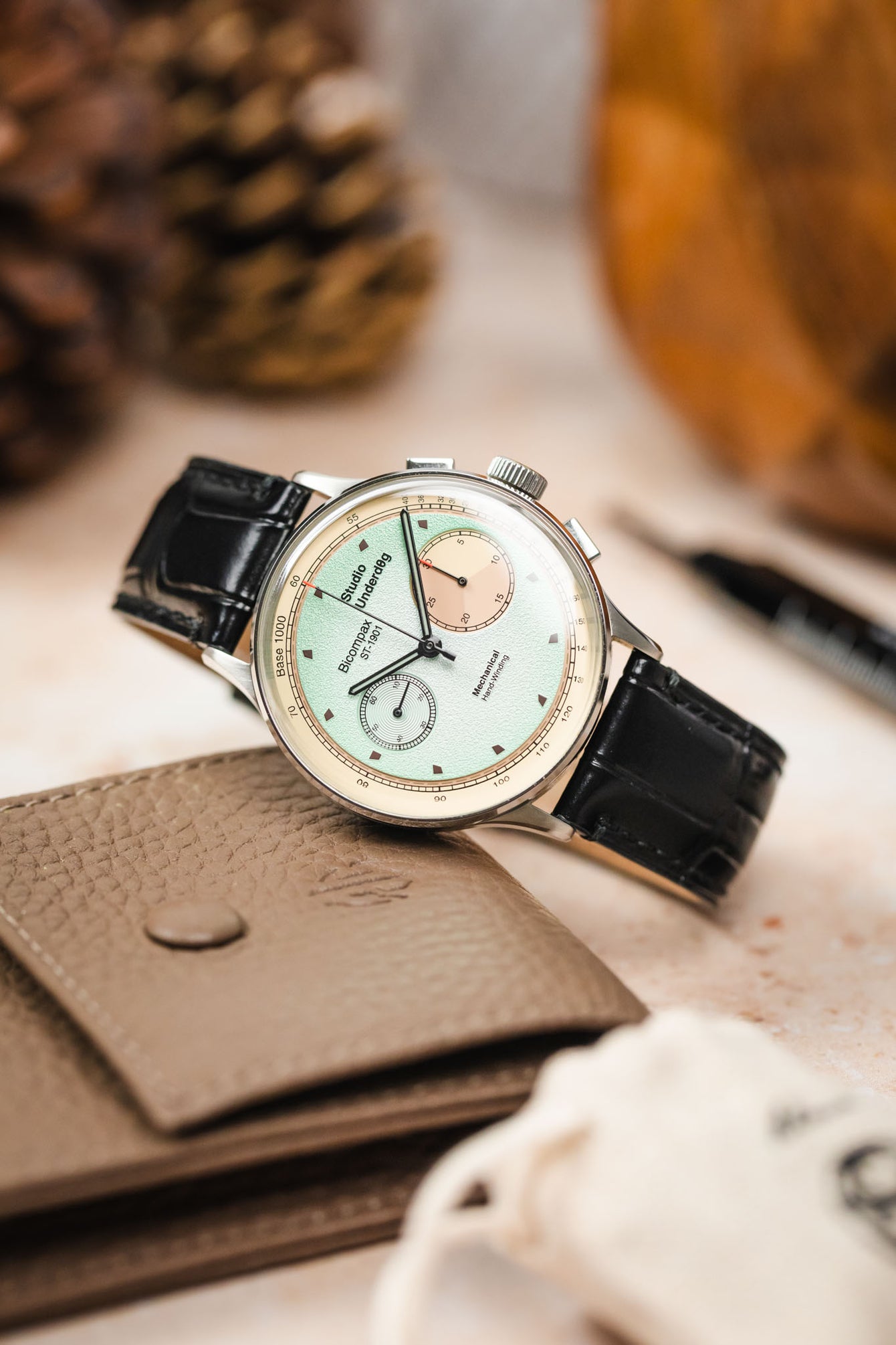 Luxury black Morellato Tiepolo watch strap and watch photographed with pine cones and a brown wallet on a table.