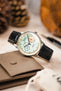 Luxury black Morellato Tiepolo watch strap and watch photographed with pine cones and a brown wallet on a table.