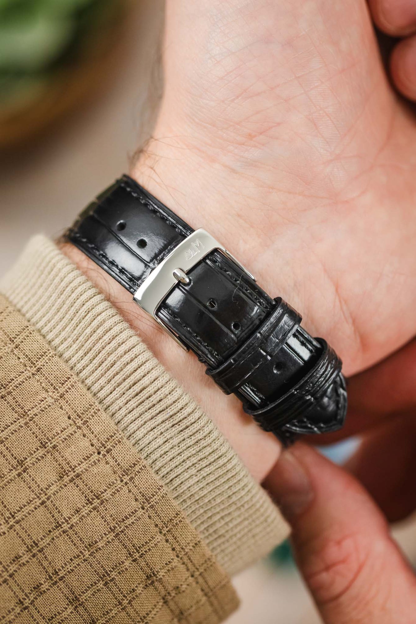 Close-up of a person's wrist wearing the black Morellato Tiepolo watch strap and a watch. Focus on the polished buckle.