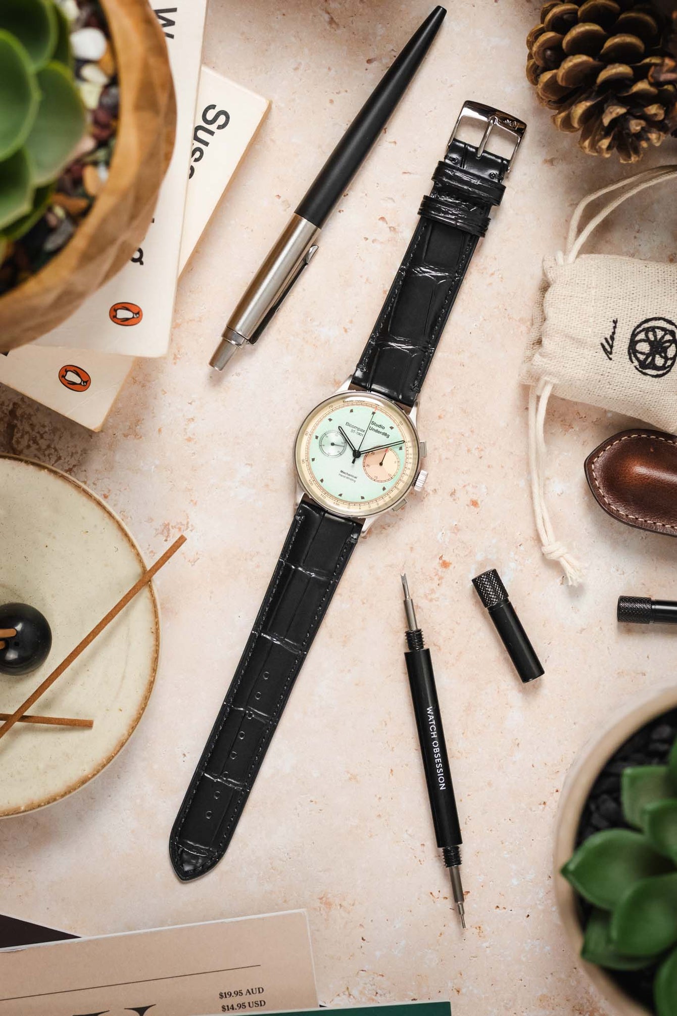 Black Tiepolo crocodile grain strap with a Studio Underdøg watch laid out on a table with other watch accessories.