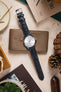 A Seiko Presage watch with the blue Morellato Tiepolo strap laid out with a brown wallet and other accessories.