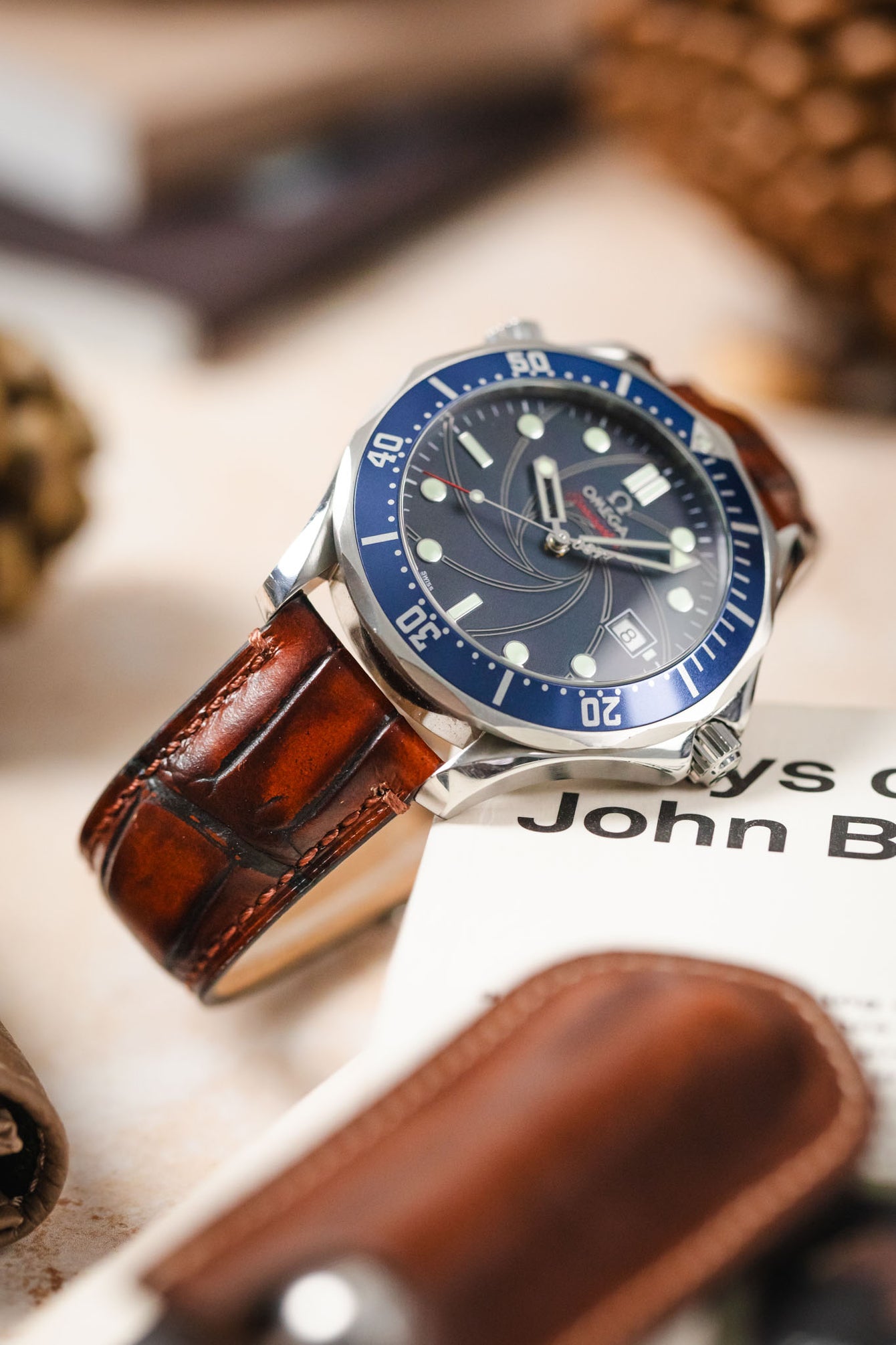 Omega Seamaster watch paired with a light brown Morellato Tiepolo watch strap on a table with accessories.