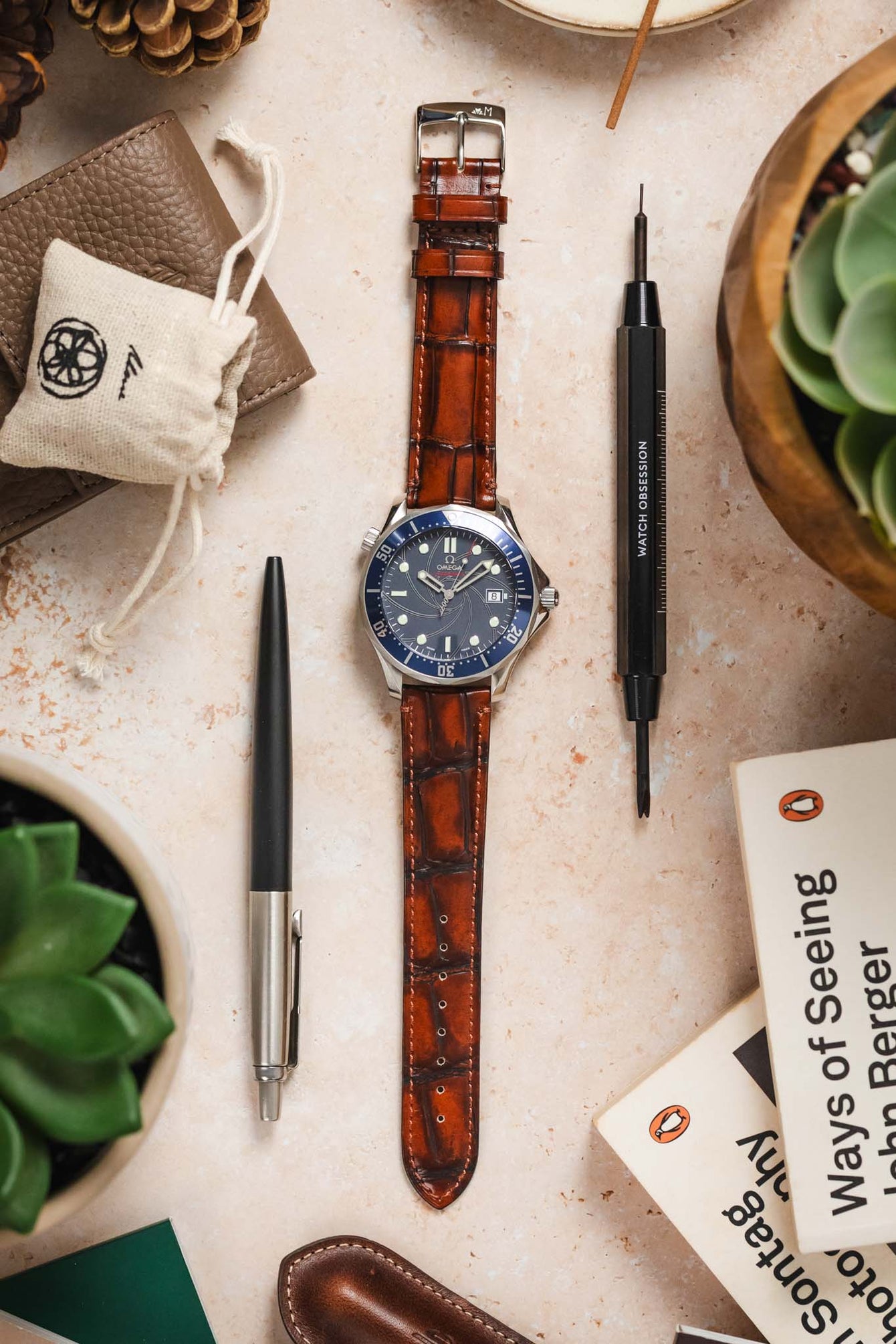 Light brown Morellato Tiepolo watch strap with an Omega Seamaster watch, photographed with pens and tools.