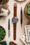 Light brown Morellato Tiepolo watch strap with an Omega Seamaster watch, photographed with pens and tools.