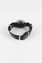 A product shot of a speedmaster shown on it's nylon one piece strap in black and orange against a white background.