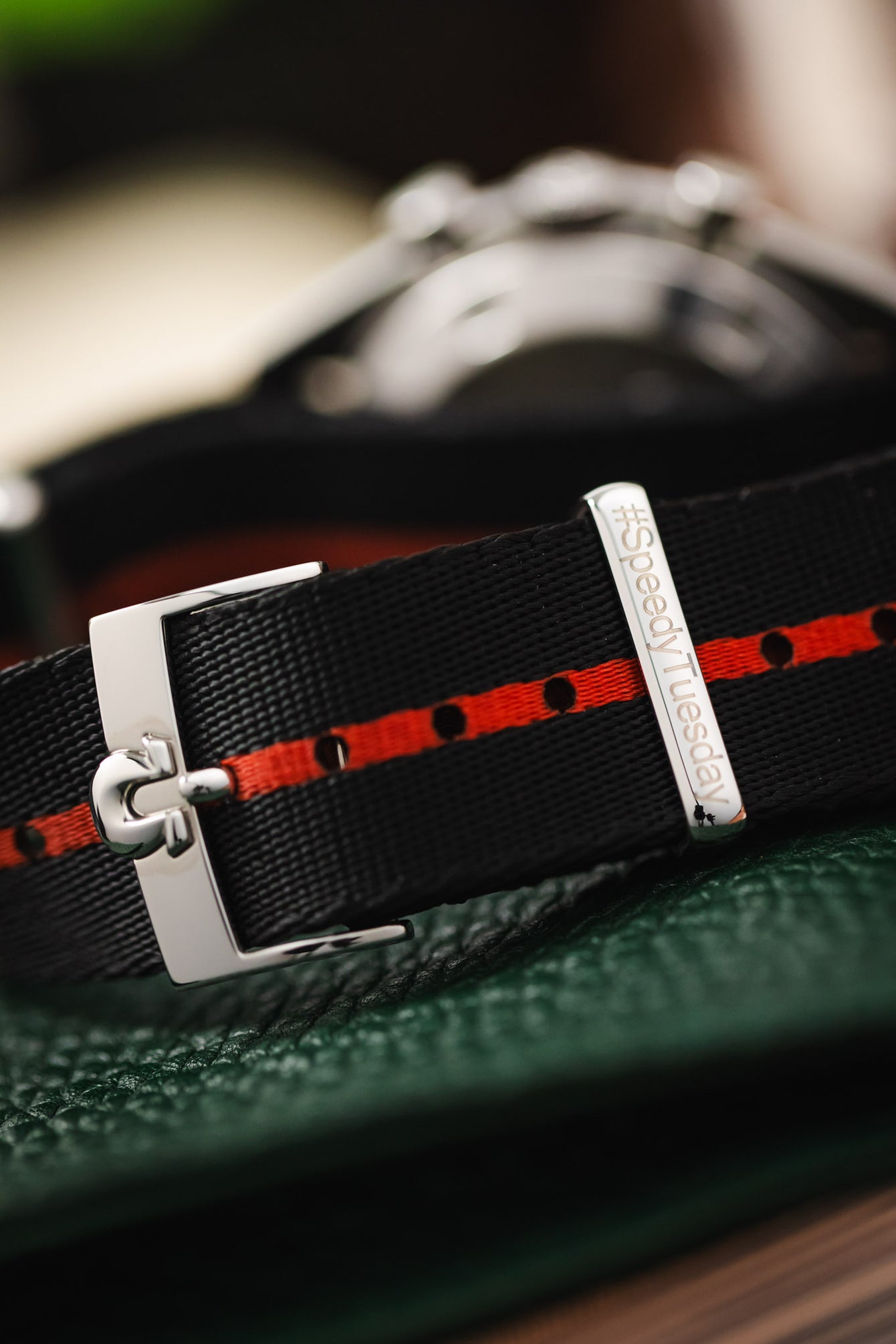 A macro photograph of the buckle on an Omega Ultraman showing the #SpeedyTuesday engraving on the polished steel hardware.