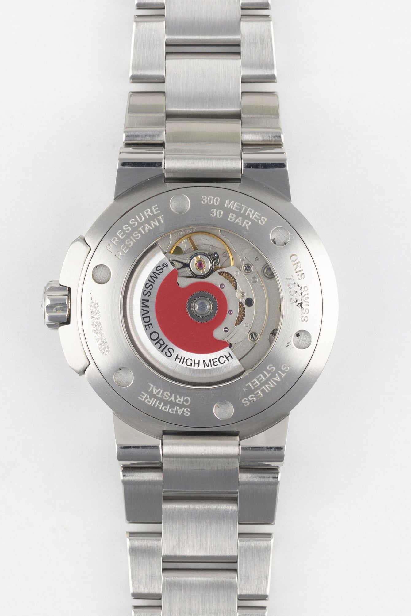 A clear, direct shot of the exhibition case back of an Oris Aquis Date, revealing the automatic mechanical movement and the iconic red Oris rotor.