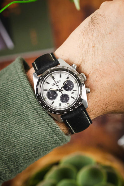 A wrist shot of a Seiko chronograph watch on a black RIOS1931 Montana leather strap with white stitching.