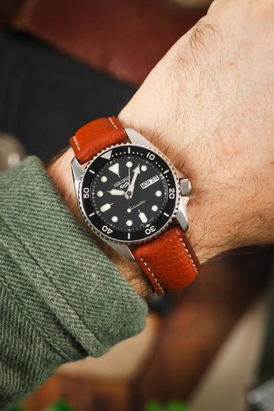 A wrist shot of a Seiko diving watch on a cognac-colored RIOS1931 Montana leather strap with white stitching.
