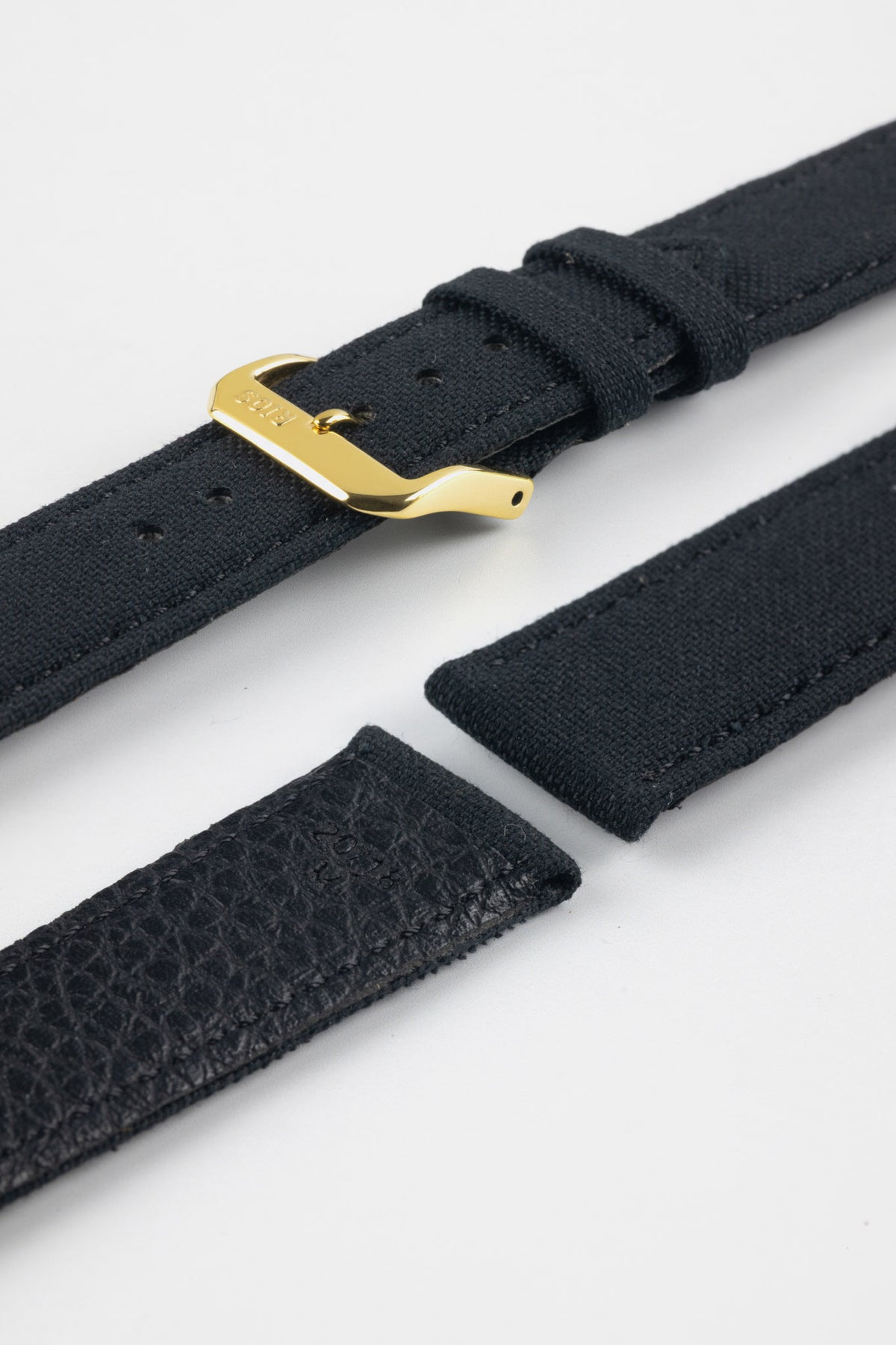 Close-up product image of a dark navy watch strap with a polished gold buckle. The strap is shown in separated sections, highlighting the fabric exterior, stitching details, adjustment holes, and textured leather underside against a light gray background.