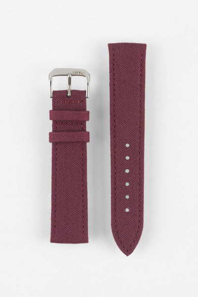 Front view of a burgundy fabric watch strap displayed in two separate pieces on a light gray background. The strap features a woven textile texture, stitched edges, a polished silver-tone RIOS-branded buckle, and two matching fabric keepers. The adjustment section includes six sizing holes and a pointed tip, showcasing the strap’s clean design and durable construction.