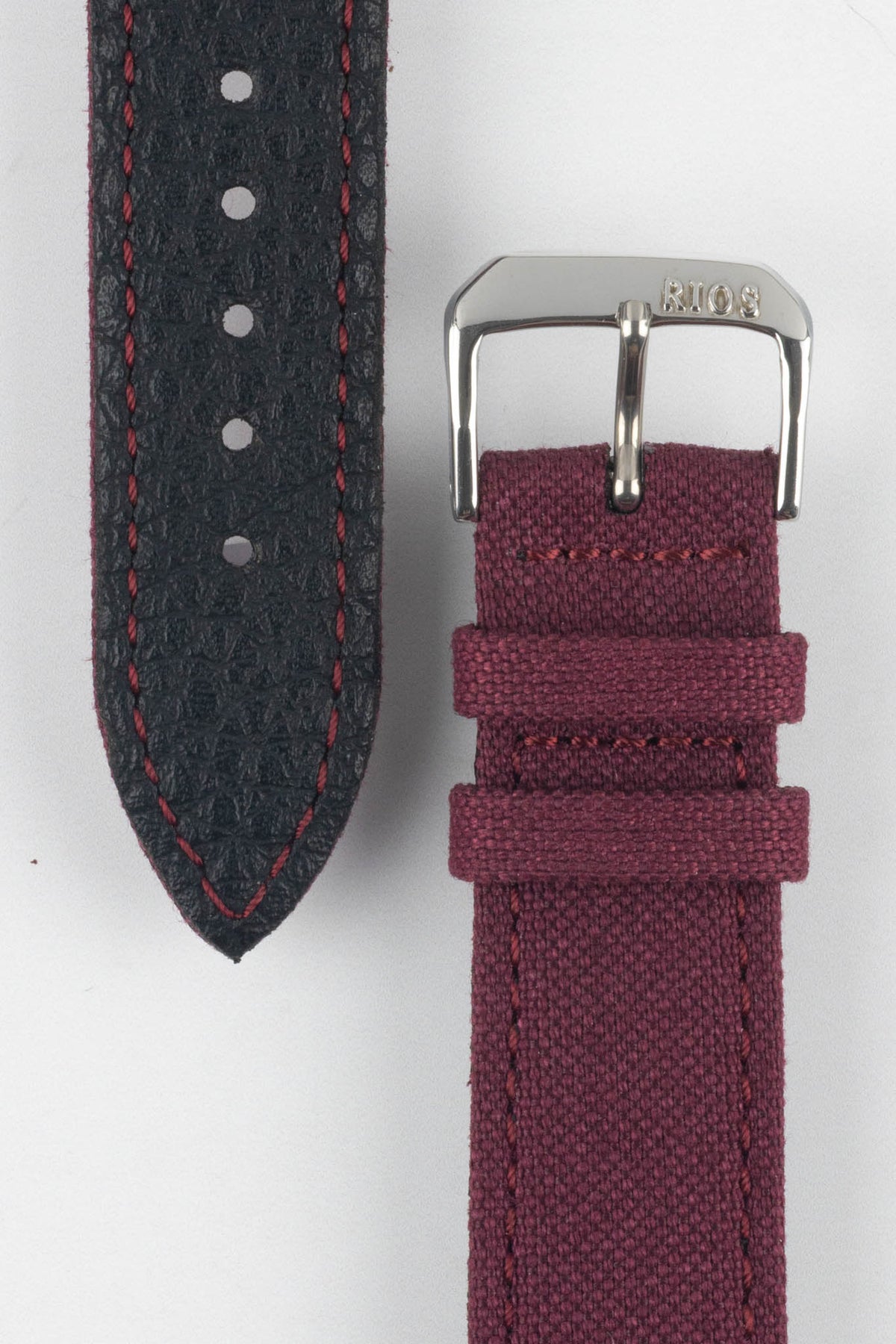 Close-up view of a burgundy fabric watch strap showing both sides on a light gray background. The woven fabric upper section features a polished silver-tone RIOS-branded buckle and two matching fabric keepers, while the black textured leather underside displays burgundy contrast stitching, adjustment holes, and a pointed tip. The image highlights the strap’s materials, stitching details, and premium craftsmanship.