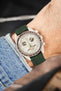 Omega x Swatch MoonSwatch Mission to Jupiter on an olive green canvas strap, shown on wrist with a cream dial and beige case.