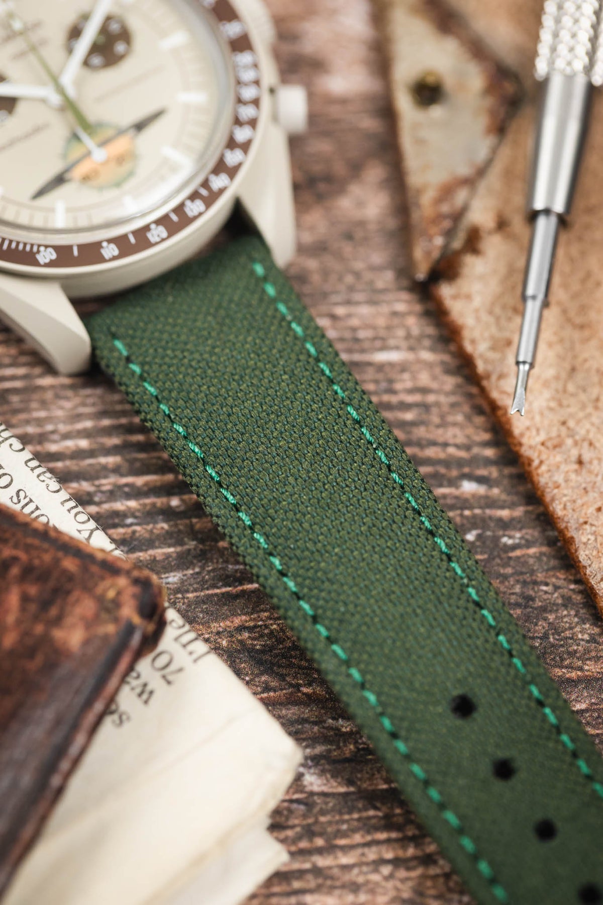 Olive green canvas watch strap fitted to an Omega x Swatch MoonSwatch Mission to Jupiter, highlighting the woven texture and green contrast stitching.