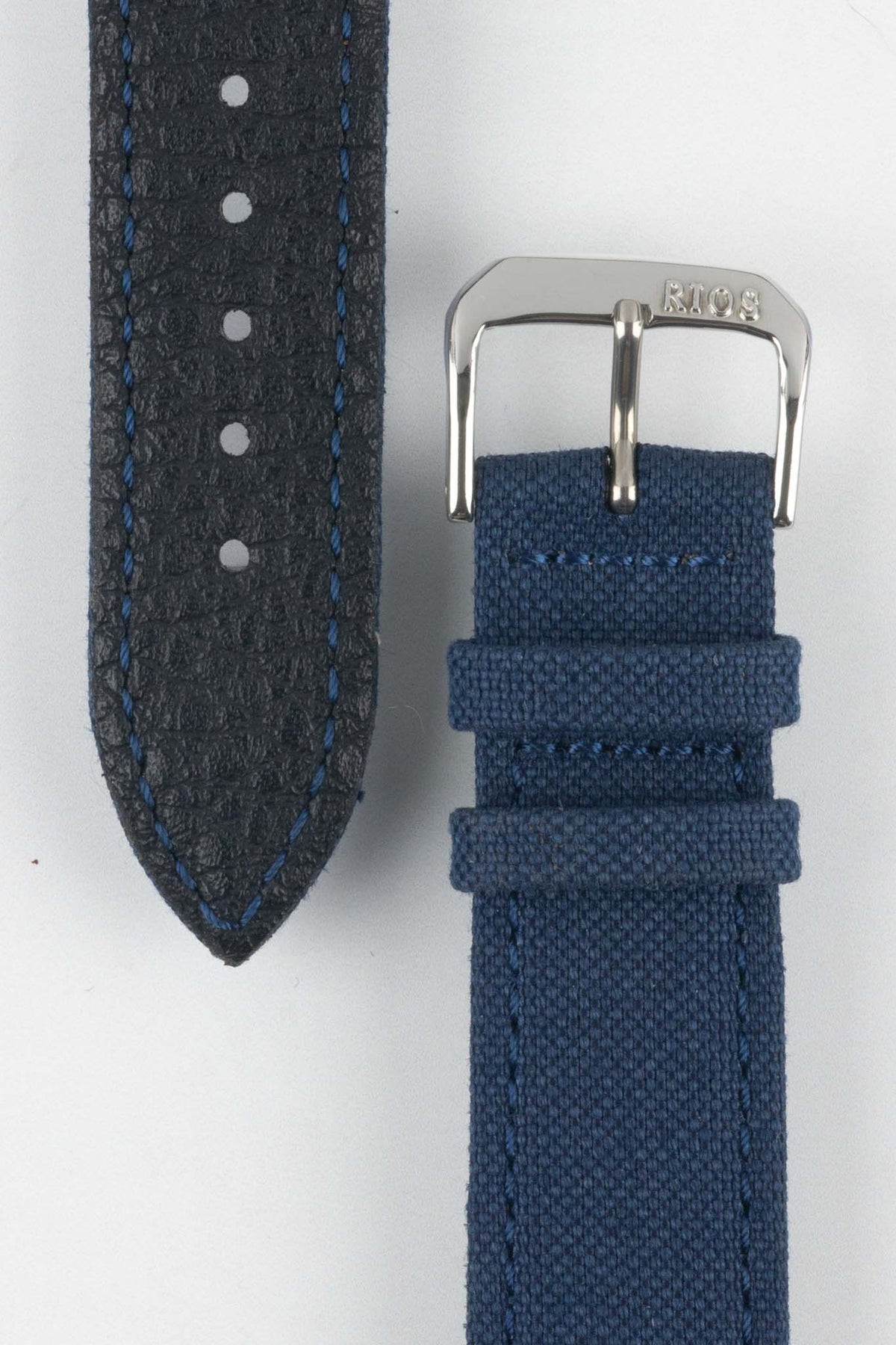 Close-up view of an ocean blue watch strap showing both sides on a light gray background. The black textured leather underside with blue contrast stitching, adjustment holes, and pointed tip is displayed alongside the woven fabric upper section featuring a polished silver-tone RIOS-branded buckle and two matching fabric keepers. The image highlights the strap's materials, stitching details, and premium construction.