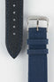 Close-up view of an ocean blue watch strap showing both sides on a light gray background. The black textured leather underside with blue contrast stitching, adjustment holes, and pointed tip is displayed alongside the woven fabric upper section featuring a polished silver-tone RIOS-branded buckle and two matching fabric keepers. The image highlights the strap's materials, stitching details, and premium construction.