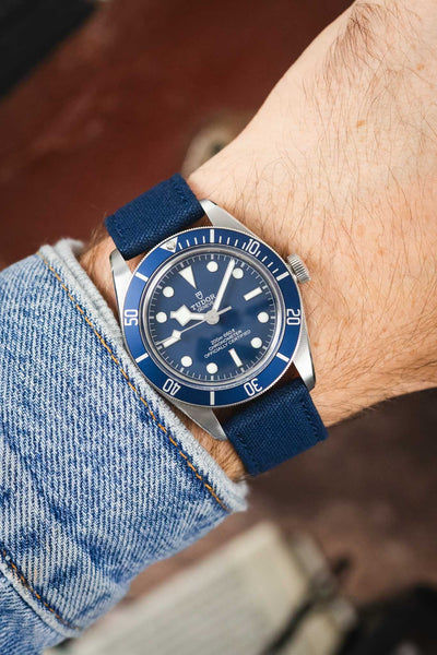 Tudor Black Bay dive watch on an ocean blue canvas strap, shown on wrist with a blue dial and matching blue bezel.