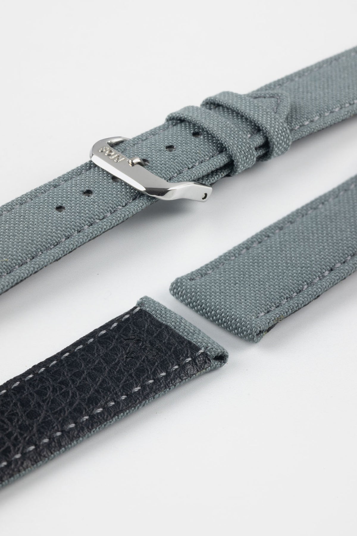 Stone grey fabric watch strap with a silver-tone RIOS buckle, shown with a black leather underside and contrast stitching.
