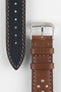 Front and back detail view of a cognac brown perforated leather rally watch strap featuring matching brown stitching, a black leather lining, dual keeper loops, and a polished stainless steel RIOS buckle, displayed on a light grey background to highlight the vintage motorsport-inspired design, contrasting underside, and premium handcrafted construction.
