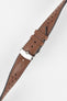 Close-up product shot of a brown perforated leather watch strap with contrast stitching, fitted with a polished silver deployment clasp. The strap is laid diagonally on a plain light background, highlighting the leather grain, perforations, stitching detail, and metal clasp.