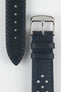 Close-up product shot of a blue-black perforated leather watch strap paired with a black underside strap segment, both featuring blue contrast stitching. A polished silver pin buckle is attached to the main strap, and the components are arranged on a plain light background to highlight the leather texture, perforations, stitching detail, and buckle hardware.