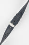 Close-up product shot of a grey-blue perforated leather watch strap with blue contrast stitching, fitted with a polished silver deployment clasp. The strap is laid diagonally on a plain light background, highlighting the textured leather surface, stitching detail, perforations, and metal clasp hardware.