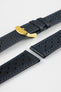 Close-up product shot of blue-black perforated leather watch strap components with blue contrast stitching, including one fitted with a polished gold-tone deployment clasp. Additional strap sections, including one with a black underside, are arranged on a plain light background, highlighting the leather texture, perforations, stitching detail, and gold clasp hardware.