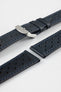 Close-up product shot of blue-black perforated leather watch strap components with blue contrast stitching, including one fitted with a polished silver deployment clasp. Additional strap sections, including one with a black underside, are arranged on a plain light background, highlighting the textured leather, perforations, stitching detail, and metal clasp hardware.