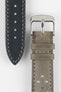 Close-up product shot of a grey suede perforated leather watch strap alongside a black underside strap segment, both with contrasting stitching. A polished silver pin buckle is attached to the grey strap, and the components are arranged on a plain light background to highlight texture, perforations, and finishing details.